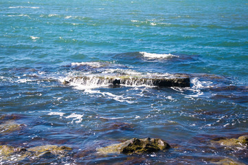 rocky sea shore with pebble beach, waves with foam