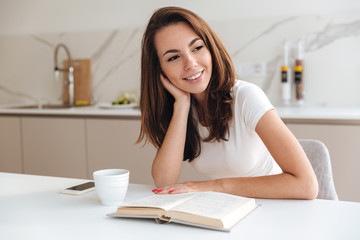 Smiling girl reading a book while sitting at the table