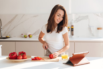 Happy young woman cutting vegetables for the salad