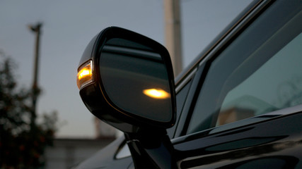 Car rear-view mirror. Direction indicator is flashing at evening. Modern car interior