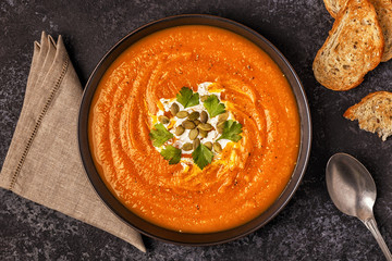 Pumpkin and carrot soup with cream, seeds and parsley.