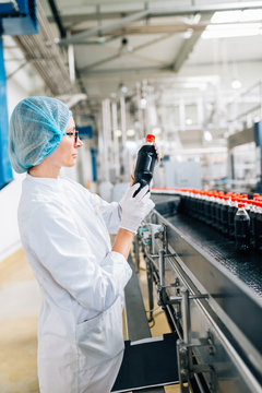 Young happy female worker in bottling factory checking water bottles or gallons before shipment. Inspection quality control. 