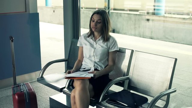 Overwhelmed, sad businesswoman by too much paperwork sitting at the train station
