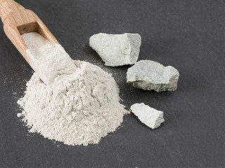 Zeolite natural  raw stones and powder on black stone  background.