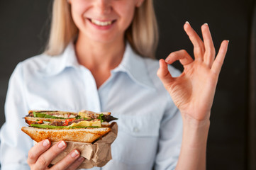 girl showing ok holding a sandwich