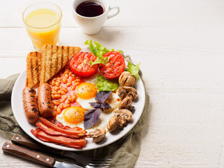 Full English Breakfast including sausages, grilled tomatoes and mushrooms, egg, bacon, baked beans, bread with orange juice