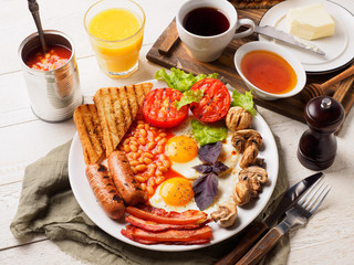 Full English Breakfast including sausages, grilled tomatoes and mushrooms, egg, bacon, baked beans, bread with orange juice