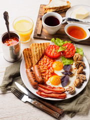 Full English Breakfast including sausages, grilled tomatoes and mushrooms, egg, bacon, baked beans, bread with orange juice
