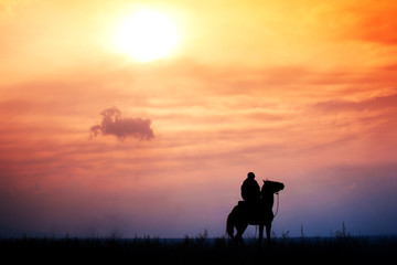 Obraz na płótnie Canvas rider on horseback in a steppe during colorful sunset, Kazakhstan