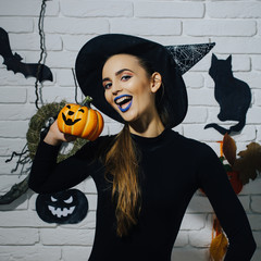 Halloween girl smiling in witch hat and black bodysuit