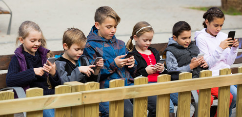 Children sitting with mobile devices in street