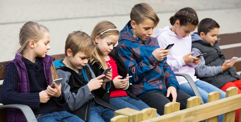 Outdoor portrait of girls and boys playing with phones