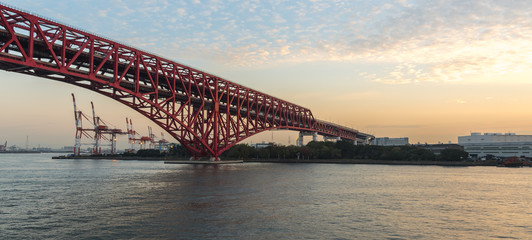 View along a red steel bridge across the River with Shipping port in sunset time,Japan