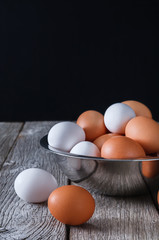 Fresh brown eggs in bowl on wood at black background