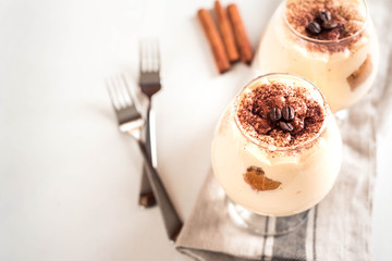 Exquisite Italian dessert tiramisu in cognac glasses on a white