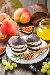 Appetizer of figs and goat cheese with honey. Layered salad of gourmet. Pears, grapes and rosemary on the table. Selective focus