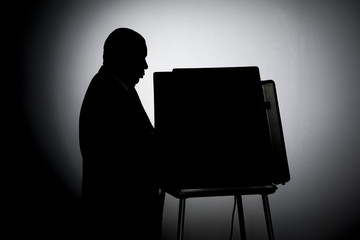 Man voting in a voting booth, silhouette shot