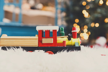 Toy train driving christmas present on snow, holiday background