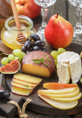 Set of fine cheeses with fruit and honey. Camembert. Bree. Grapes, figs, pears, and rosemary. Wine snacks for foodies. Selective focus