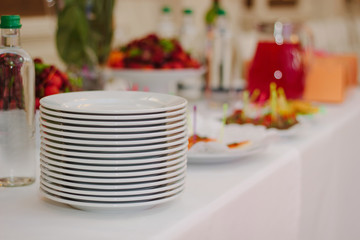 Pile of white plates on catering buffet.