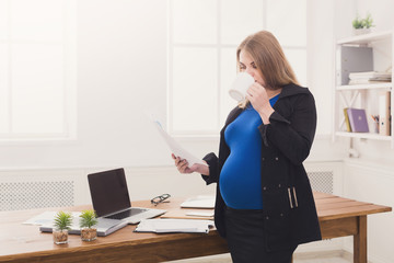 Pregnant business woman talking on phone with cup