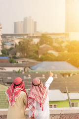 Fototapeta na wymiar Two arab businessman on muslim suit pointing at building and talking about business plan for future