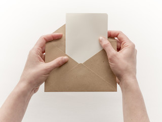 Female hands put the letter in the craft envelope, isolated on white