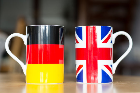 German and Great Britain flag on two mugs with blurry background