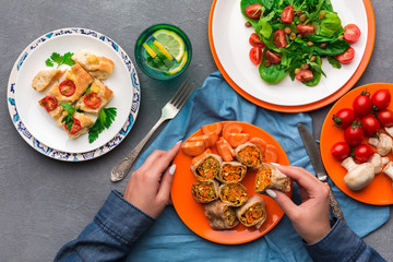 Woman eating healthy food on gray background, top view.