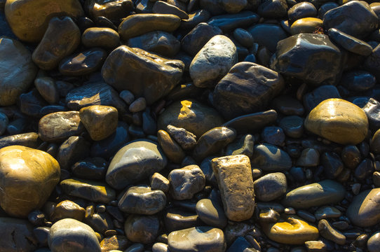 Fototapeta rocky sea shore with pebble beach, waves with foam
