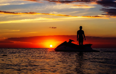 silhouette of a man on a jet ski in the sun