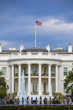 Washington DC, USA. White House view on cloudy day background and american flag.