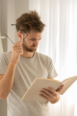 Man reading a book in his living room ,feeling excited and surprised