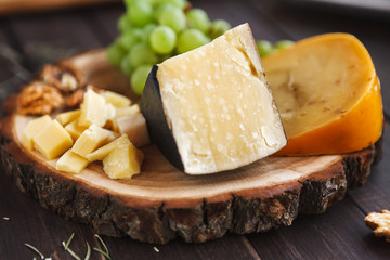 Cheese platter, parmesan on natural wood disc with grapes and nuts
