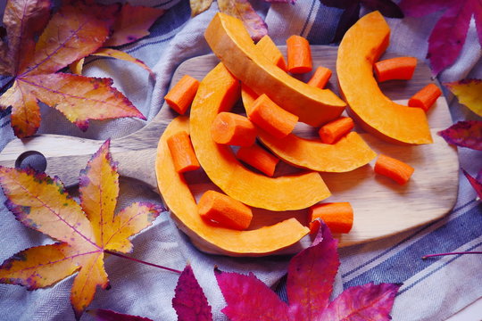 Pumpkin and carrot Slices. Fresh autumn vegetables. Composition of pumpkin and carrot on the wooden cut board. Autumn food composition with yellow leaf. Happy Thanksgiving composition.