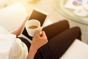Closed up ,Business woman drinking coffee with tablet computer sitting on sofa in living room