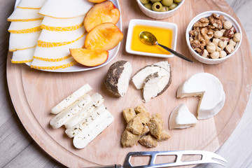 Cheese plate. 4 types of cheese, melon, nectarine, nuts, olives. Close-up. Selective focus.