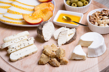 Cheese plate. 4 types of cheese, melon, nectarine, nuts, olives. Close-up. Selective focus.