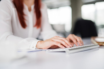 Unrecognizable businesswoman in the office writing something.