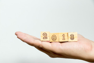 Man hold wood block with wording 2018 on concrete background (Concept for Happy new year 2018)