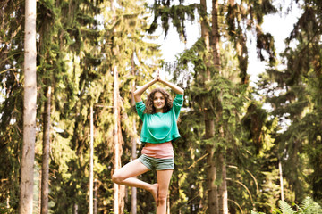 Beautiful girl practices yoga in the morning forest.