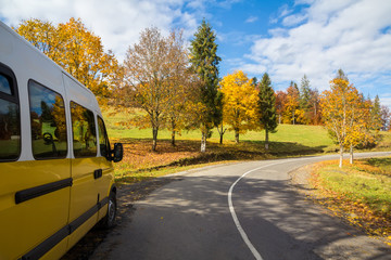 Obraz premium Yellow bus on the turn of autumn road outside the city