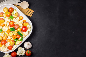 Various vegetables - tomatoes, cauliflower, zucchini, potato on dark background. Top view, copy space.