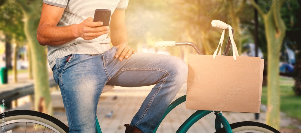 Fototapete composite image of man using phone while sitting on bicycle