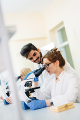 Young scientist looking through microscope in laboratory