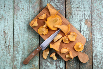 Fresh chanterelle mushrooms cut with wooden handle knife on old shabby turqoiuse boards