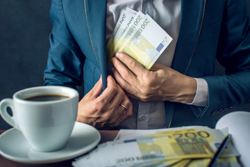 Man Businessman in suit puts money in his pocket. A bribe in the form of Euro bills. Concept of...