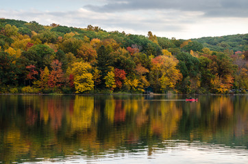 Lonely Canoe on a Mountain Lake with Wooded Shores in Autumn. Great Reflection in Water