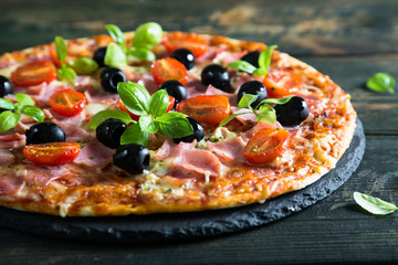 Pizza on a thin dough with olives and fresh basil