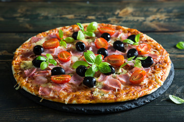 Pizza on a thin dough with olives and fresh basil